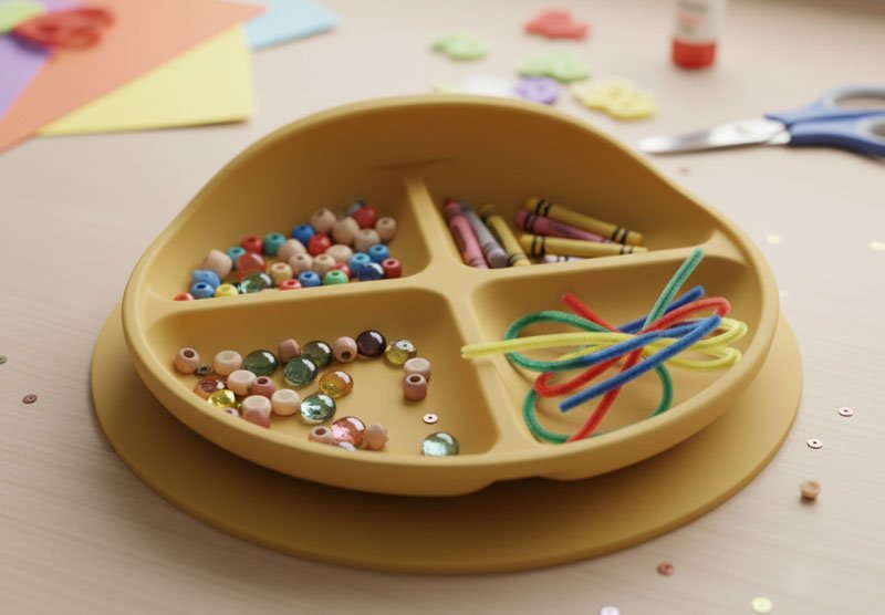 Eine alte Baby-Saugnapfplatte aus Silikon, umfunktioniert als Organizer für Bastelbedarf wie Buntstifte und Perlen.