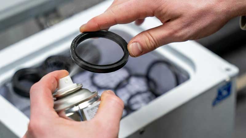 सिलिकॉन ओ रिंग पर फ्रीज स्प्रे परीक्षण करते हुए हाथ