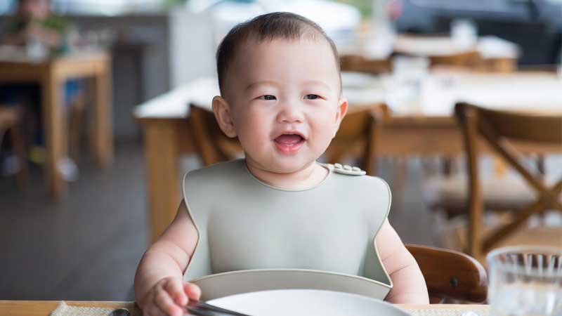 レストランや屋外カフェでシリコン製のよだれかけを着用している赤ちゃん