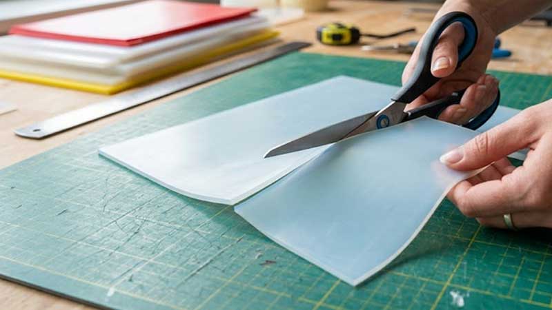des ciseaux découpant une feuille de silicone fine et souple